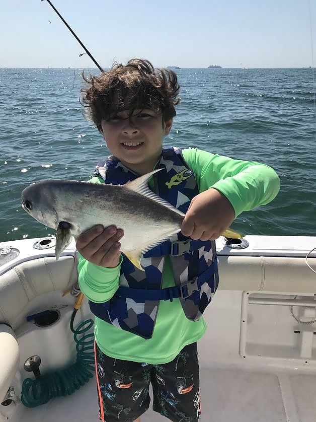 Young boy poses with fish caught on family trip.